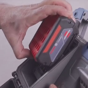 A hand inserts a red Bosch Professional battery into a tool.