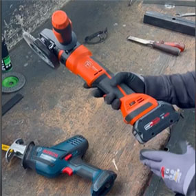Bosch Professional cordless angle grinder in orange, held on a workbench.