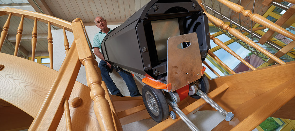 Ein Mann trägt eine schwarze Werkzeugbox die Treppe hinauf.