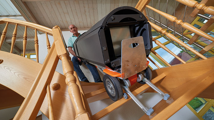 Ein Mann transportiert eine schwarze Werkzeugkiste die Treppe hinunter.