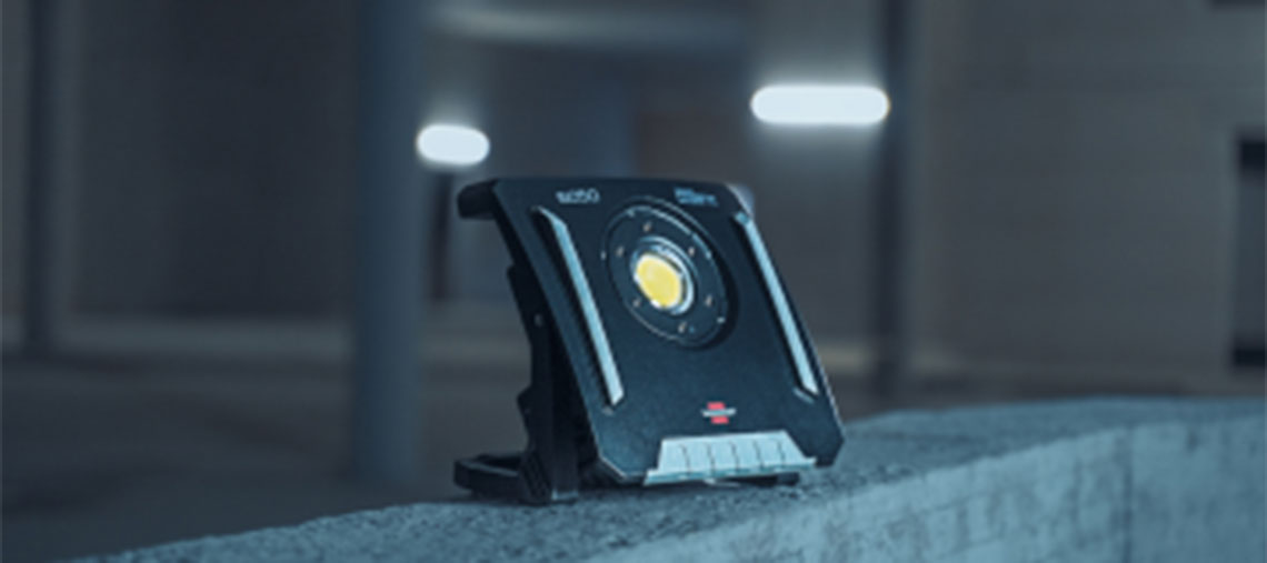 Ein schwarzer Bosch Professional Baustrahler steht auf einer Betonfläche.