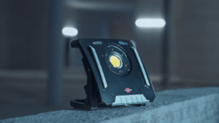 Ein schwarzer Bosch Professional Baustrahler steht auf einem Betonsockel.