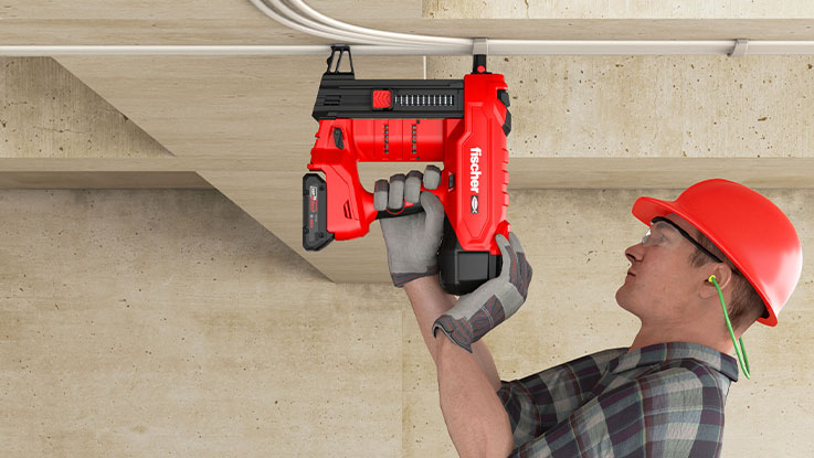 Ein Mann mit rotem Helm nutzt eine rote fischer Akku-Nagelpistole.