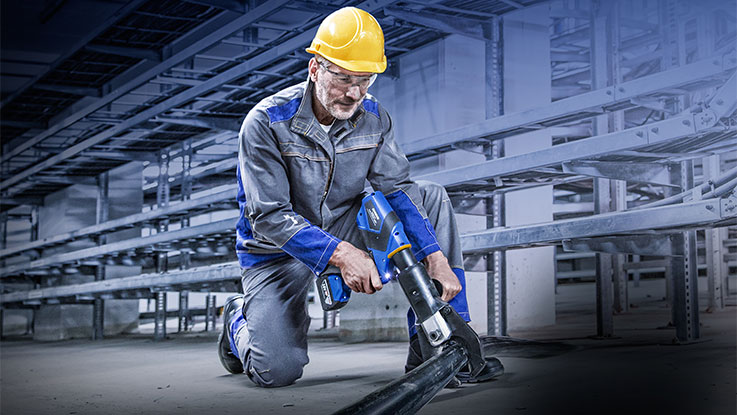 Ein Mann in Arbeitskleidung saugt mit einem blauen Bosch Werkzeug.