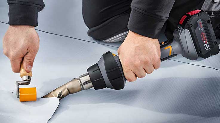 Eine Person bearbeitet mit einem Bosch Heißluftgebläse eine Folie.