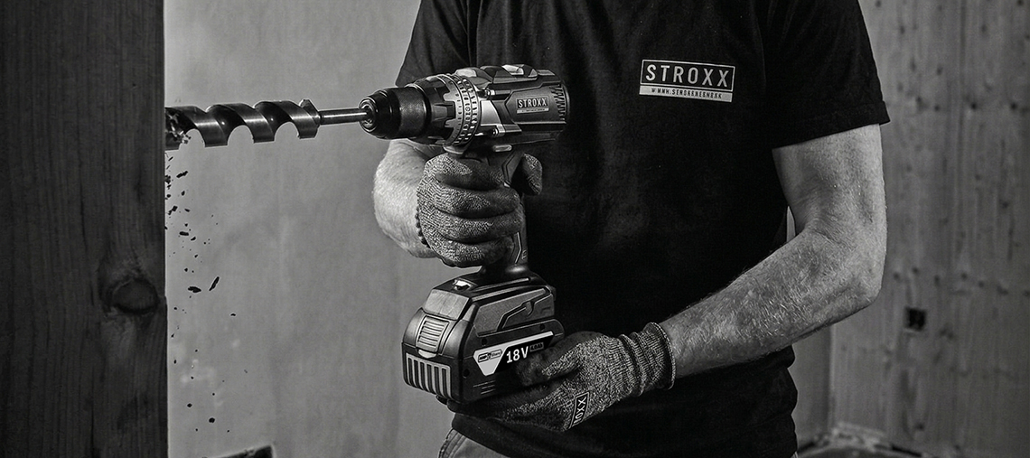 A hand holds a tool attachment with various bits. In the background, a drill is visible.